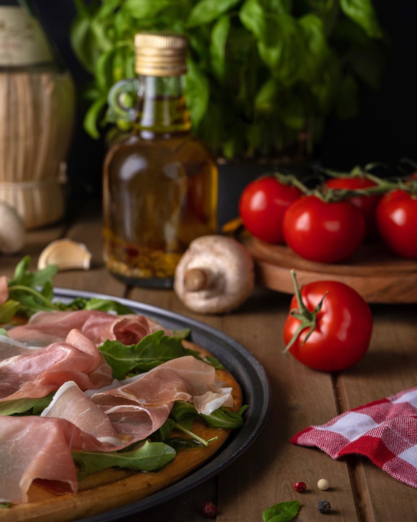 Moody food spread with oil, tomatoes, and prosciutto